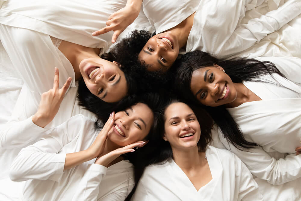 women's in white bathrobes lying in bed smile look at camera
